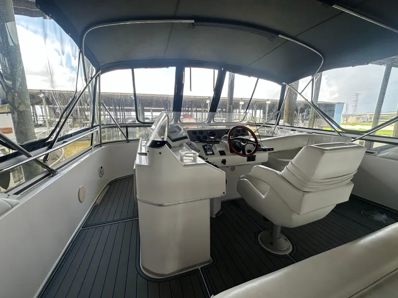 Slide: The Image of 1996 Sea Ray 440 Express Bridge helm with white seating and panoramic windows. - 16