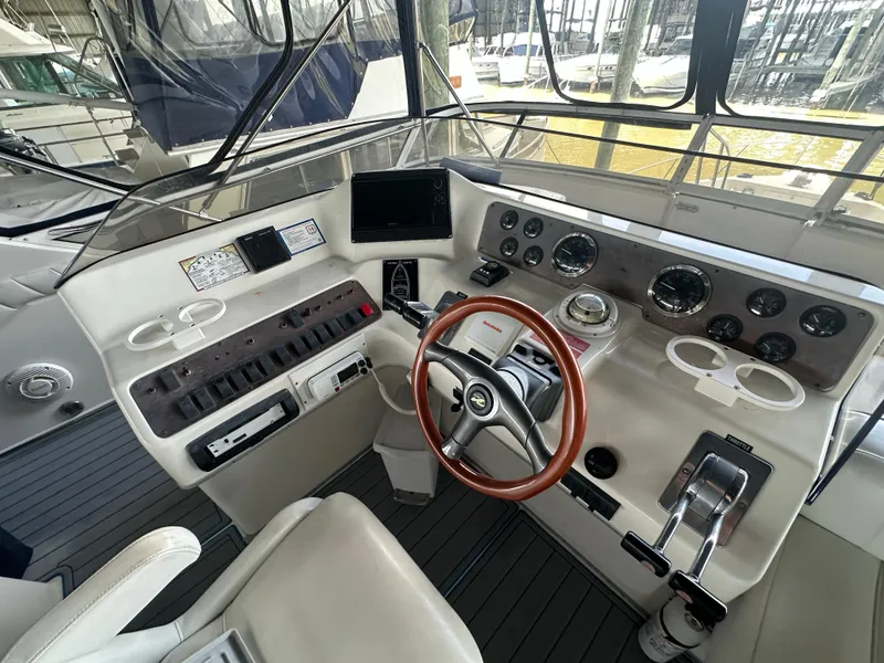 Slide: The Image of 1996 Sea Ray 440 Express Bridge helm with gauges, controls, and wooden steering wheel. - 21