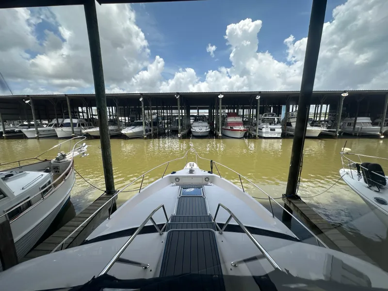 Slide: The Image of 1996 Sea Ray 440 Express Bridge docked in a marina under a cloudy sky. - 26