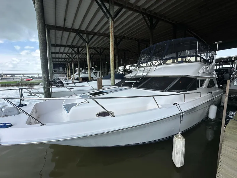 Slide: The Image of 1996 Sea Ray 440 Express Bridge yacht docked under a covered marina. - 4