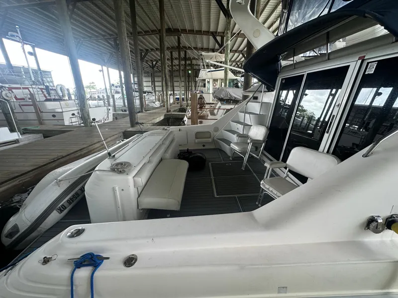 Slide: The Image of 1996 Sea Ray 440 Express Bridge docked in a covered marina, featuring spacious seating area. - 7