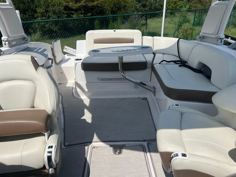 Slide: The Image of 2017 Chaparral 244 Sunesta boat interior with white and brown seating, outdoor setting. - 9