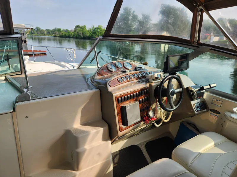 Slide: The Image of 2001 Maxum 3300 SCR boat cockpit with steering wheel, dashboard, and serene water view. - 12