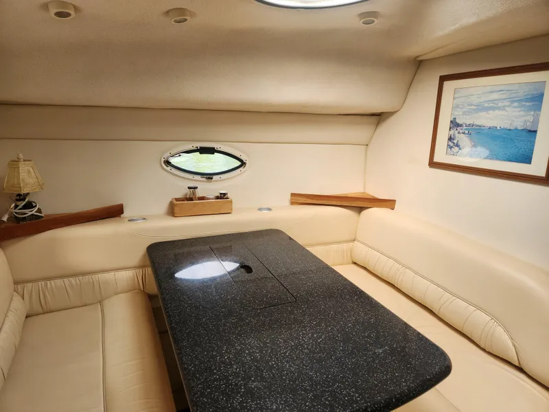 Slide: The Image of 2001 Maxum 3300 SCR cabin interior with beige seating, black table, and nautical artwork. - 22
