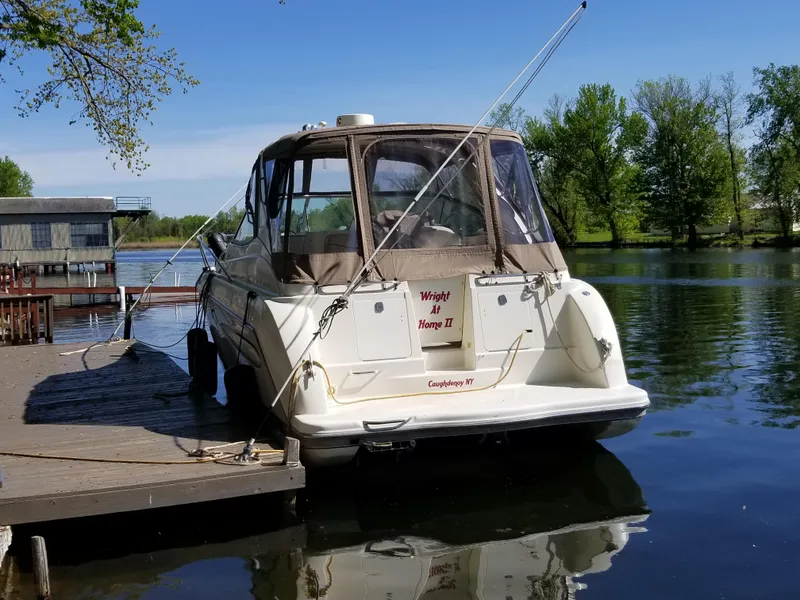 Slide: The Image of 2001 Maxum 3300 SCR boat docked on a serene lake with lush greenery. - 6