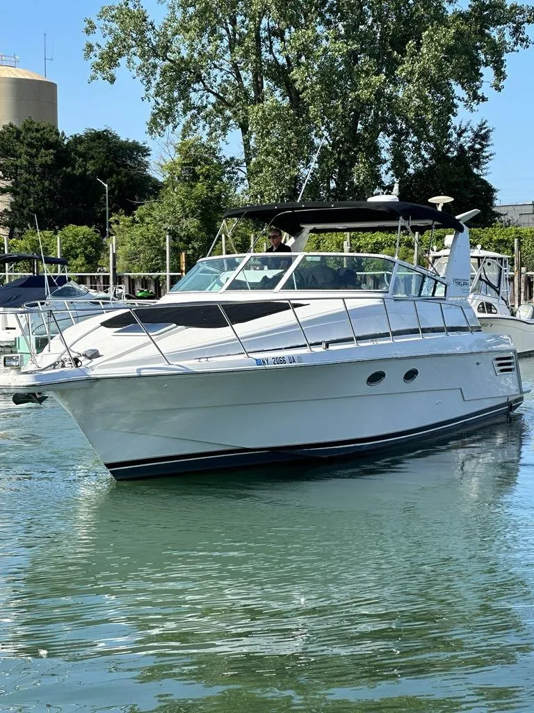 The Image of 1999 Trojan 40 Express yacht cruising on a calm waterway, surrounded by lush greenery. - 0