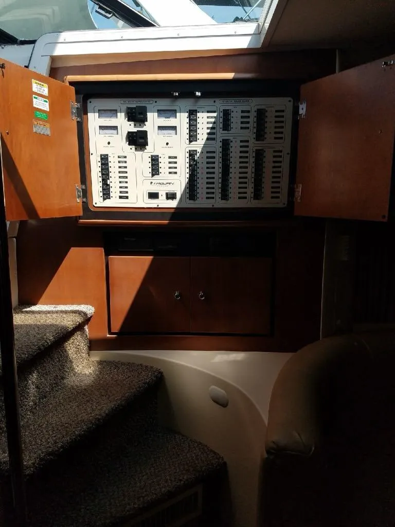 Slide: The Image of 1999 Trojan 40 Express electrical panel with open cabinet doors, carpeted stairs, and natural lighting. - 11