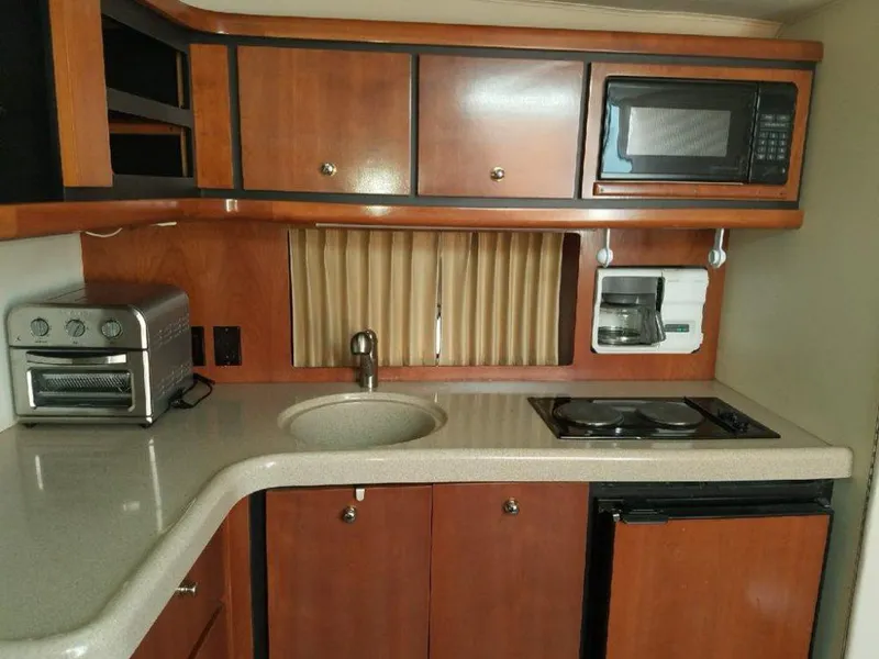 Slide: The Image of Compact kitchen in a 1999 Trojan 40 Express boat with appliances and wooden cabinetry. - 13