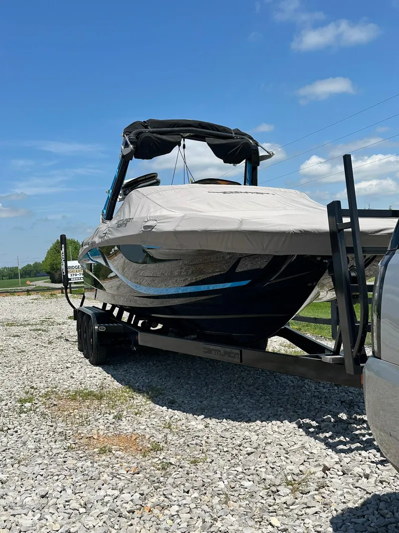 Slide: The Image of 2021 Centurion Fi25 boat on trailer, covered, parked on gravel under blue sky. - 13