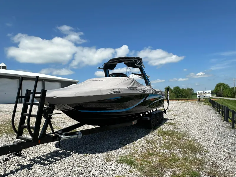 Slide: The Image of 2021 Centurion Fi25 boat on trailer, covered, parked outdoors under blue sky. - 14
