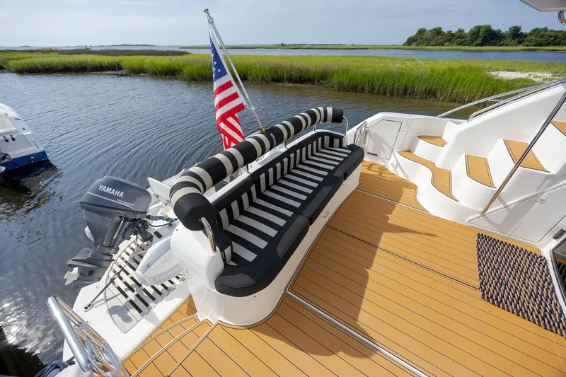 Slide: The Image of 2004 Neptunus 56 Flybridge yacht deck with striped seating and American flag. - 13