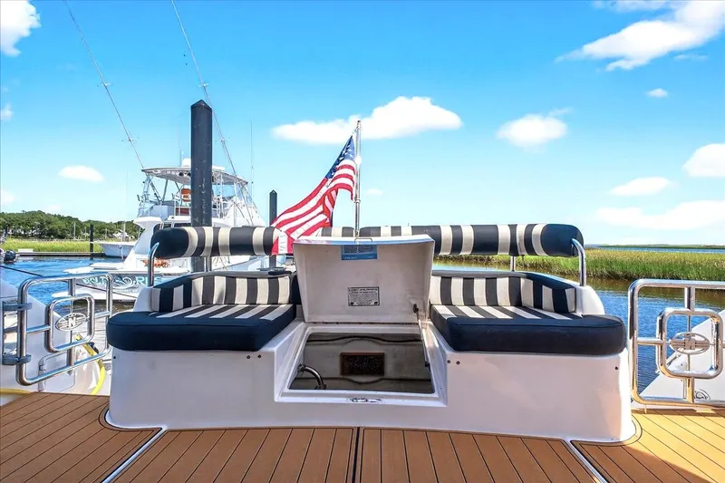 Slide: The Image of 2004 Neptunus 56 Flybridge yacht with striped seating and American flag, docked by the water. - 14