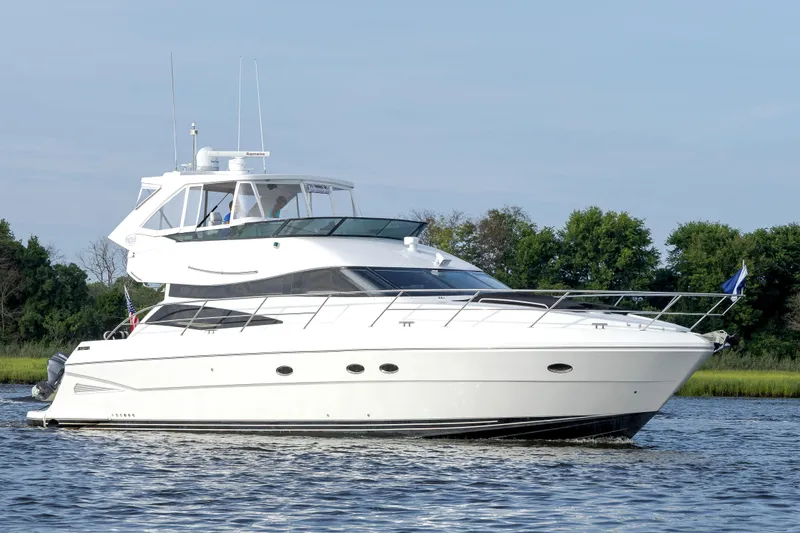 Slide: The Image of 2004 Neptunus 56 Flybridge yacht cruising on a calm river with lush greenery. - 2