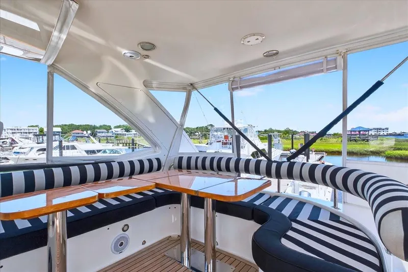 Slide: The Image of Luxurious 2004 Neptunus 56 Flybridge yacht interior with striped seating and scenic marina view. - 20