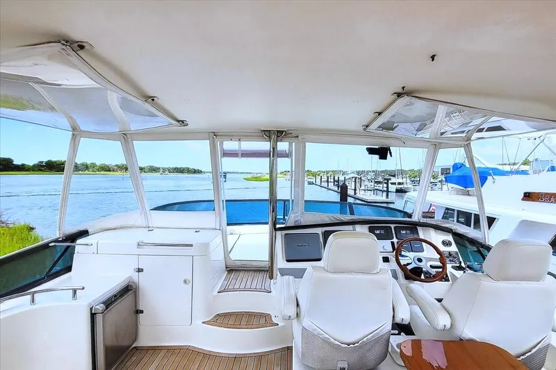 Slide: The Image of Flybridge view of 2004 Neptunus 56 yacht, featuring helm and seating, overlooking marina. - 21