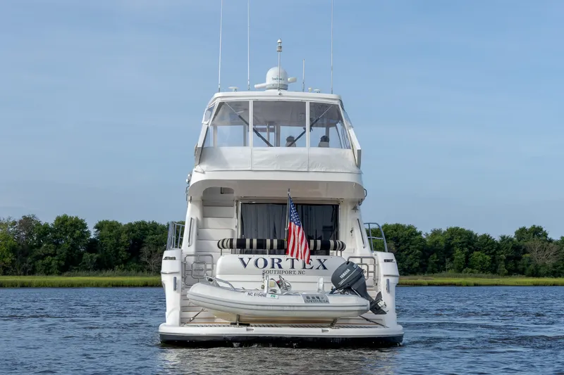 Slide: The Image of 2004 Neptunus 56 Flybridge yacht on water, rear view with American flag and tender boat. - 3