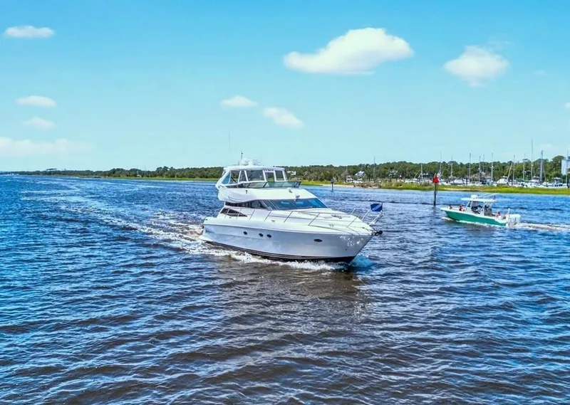 Slide: The Image of 2004 Neptunus 56 Flybridge yacht cruising on a sunny day, with a smaller boat nearby. - 6