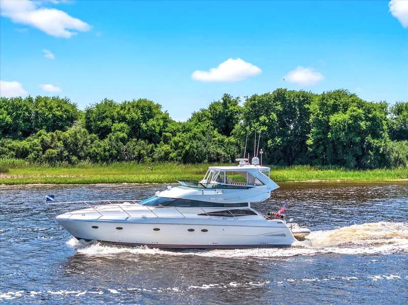 Slide: The Image of 2004 Neptunus 56 Flybridge yacht cruising on a river with lush green trees. - 7