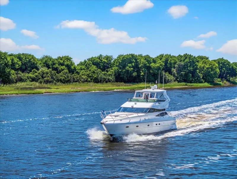 Slide: The Image of 2004 Neptunus 56 Flybridge yacht cruising on a scenic river with lush green trees. - 8