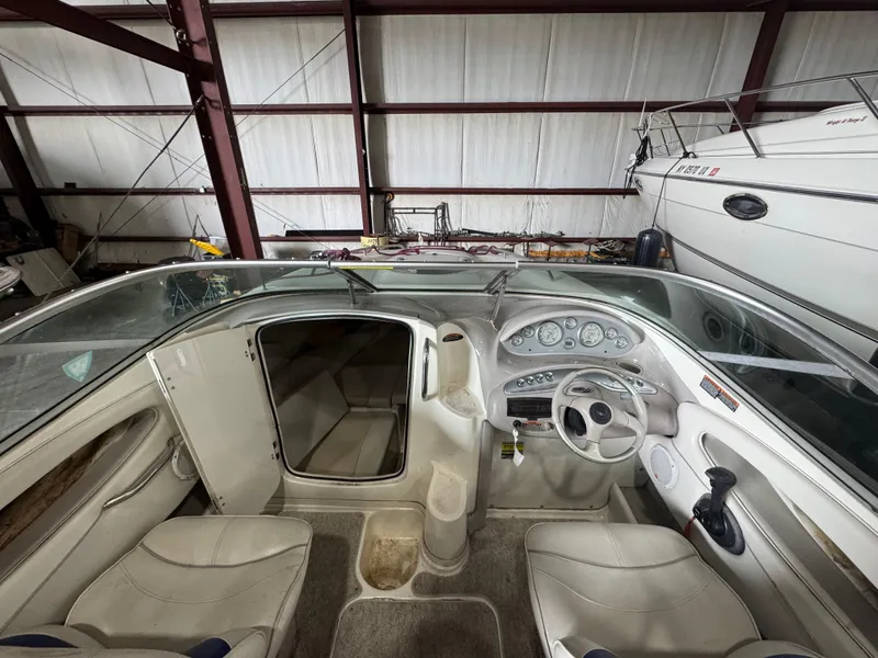 Slide: The Image of 2004 Maxum 2100 SC boat interior with steering wheel, dashboard, and seating in storage. - 3