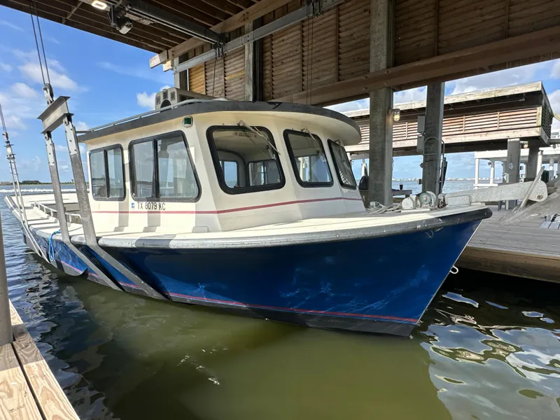 The Image of 2004 Custom Jefferson Fiberglass 32 Laffite Skiff docked under a wooden shelter. - 0