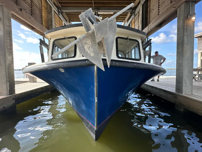 Slide: The Image of Front view of a 2004 Jefferson Fiberglass 32 Laffite Skiff docked under a wooden structure. - 10