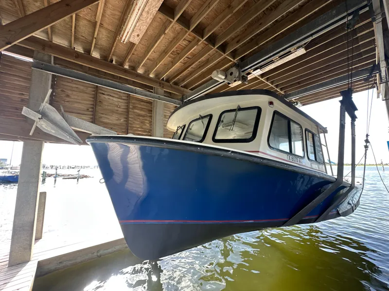 Slide: The Image of 2004 Jefferson Fiberglass 32 Laffite Skiff boat docked in a wooden boathouse. - 2