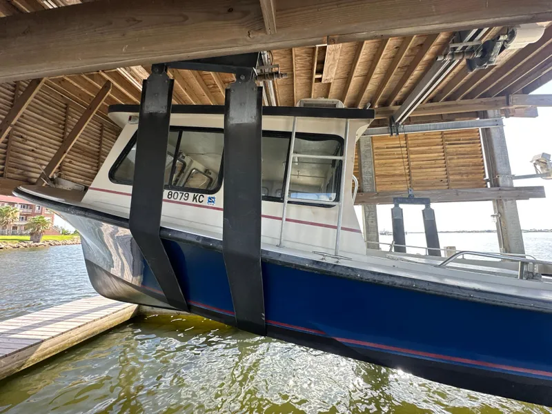 Slide: The Image of 2004 Jefferson Fiberglass 32 Laffite Skiff suspended in a boat lift under a wooden dock. - 5