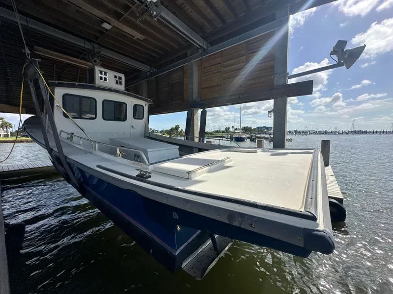 Slide: The Image of 2004 Jefferson Fiberglass 32 Laffite Skiff under a dock, sunny waterfront view. - 6