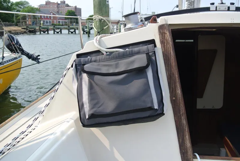 Slide: The Image of 1986 O'Day 272 sailboat cockpit with storage bag, docked near waterfront buildings. - 15