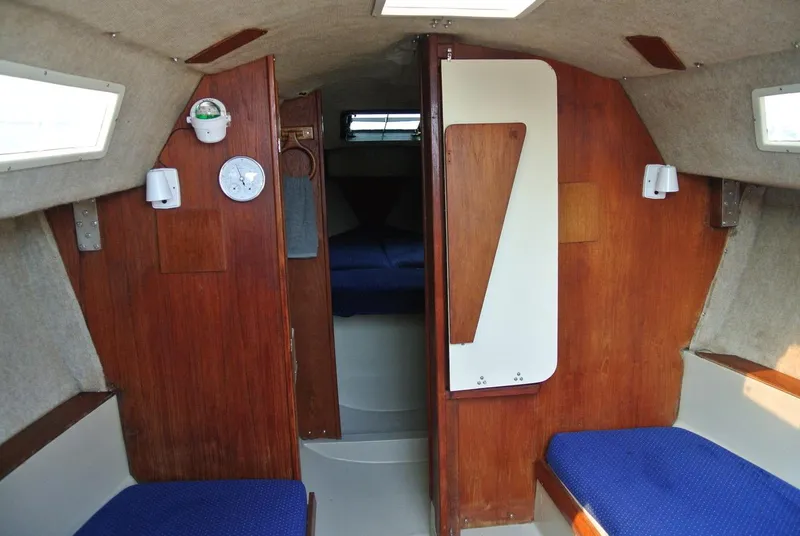 Slide: The Image of Interior of a 1986 O'Day 272 sailboat with wooden paneling and blue seating. - 22