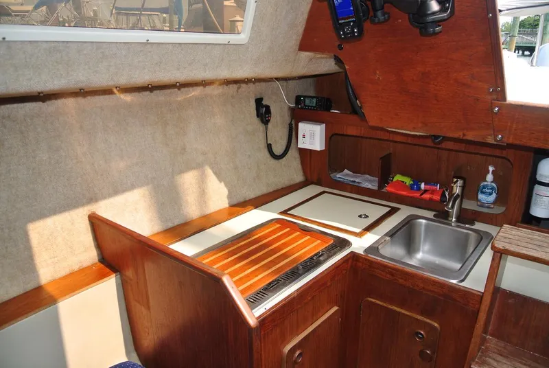 Slide: The Image of Interior of 1986 O'Day 272 sailboat galley with sink, stove, and wooden cabinetry. - 29