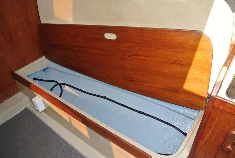Slide: The Image of 1986 O'Day 272 sailboat interior storage compartment with wooden lid and visible wiring. - 31
