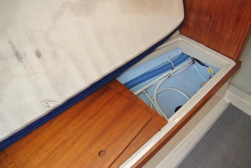 Slide: The Image of Interior storage compartment of a 1986 O'Day 272 sailboat, showing wiring and hoses. - 32