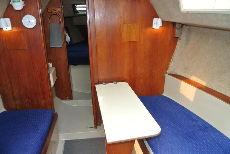 Slide: The Image of Interior of a 1986 O'Day 272 sailboat with wooden paneling and blue seating. - 33