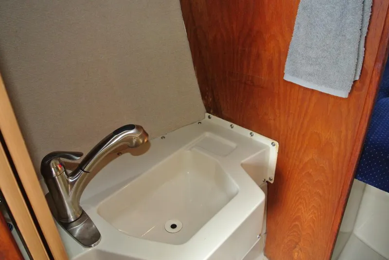 Slide: The Image of Compact sink area in 1986 O'Day 272 sailboat with modern faucet and wooden paneling. - 35
