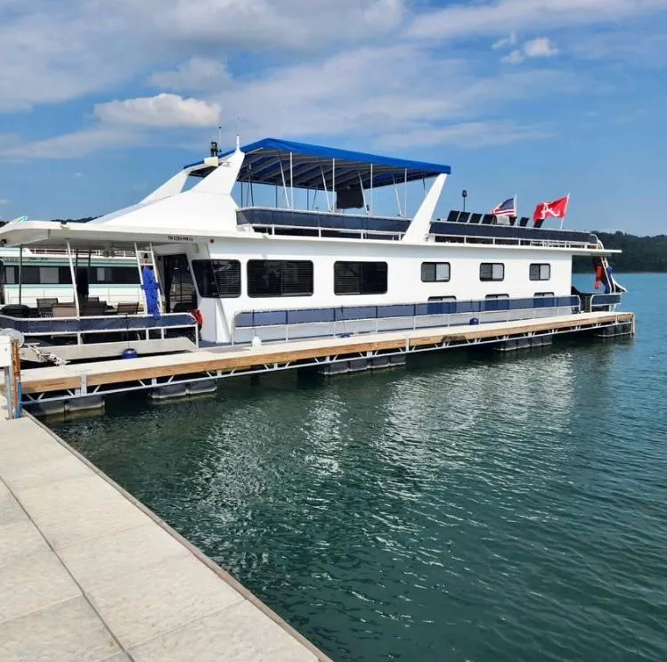 The Image of 1992 Jamestowner 16x72 houseboat docked on a sunny day with flags. - 0
