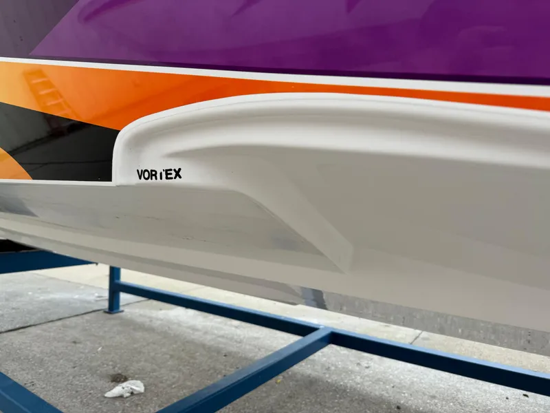 Slide: The Image of 2003 Sunsation 288 boat hull with vibrant purple, orange, and black design on display stand. - 11