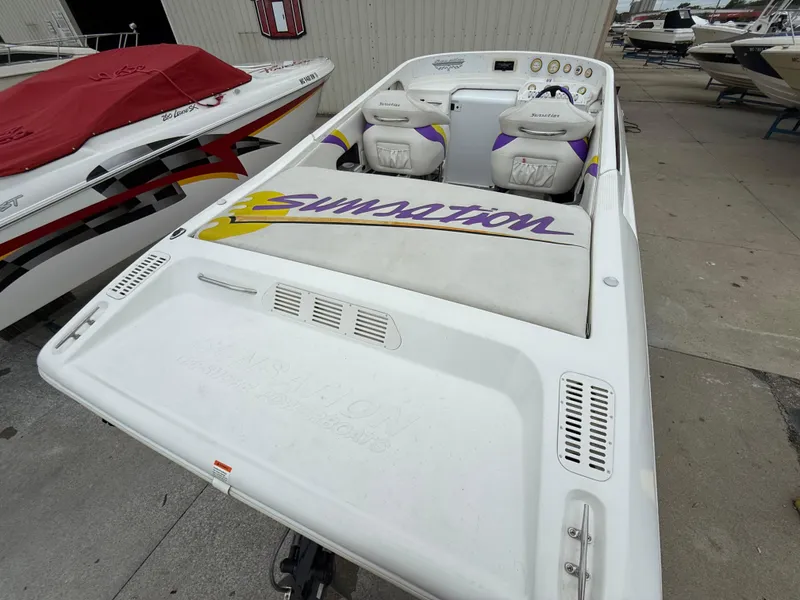 Slide: The Image of 2003 Sunsation 288 boat with custom seating and vibrant logo, docked alongside other boats. - 16