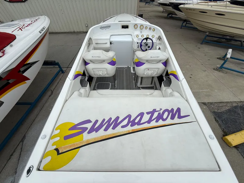 Slide: The Image of 2003 Sunsation 288 powerboat with vibrant interior and logo, docked alongside other boats. - 18