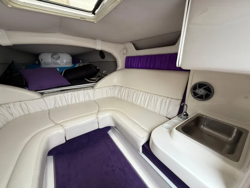 Slide: The Image of 2003 Sunsation 288 boat interior with white seating, purple accents, and a small sink area. - 29
