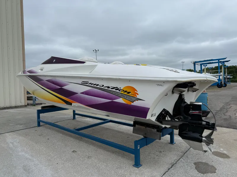 Slide: The Image of 2003 Sunsation 288 speedboat with vibrant graphics on a stand, overcast sky background. - 3