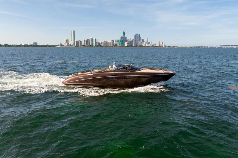 Slide: The Image of 2005 Riva 44' Rivarama yacht cruising on open water with city skyline backdrop. - 11