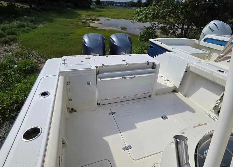 Slide: The Image of 2014 Pursuit C 280 Center Console boat with twin engines, docked near lush greenery. - 10
