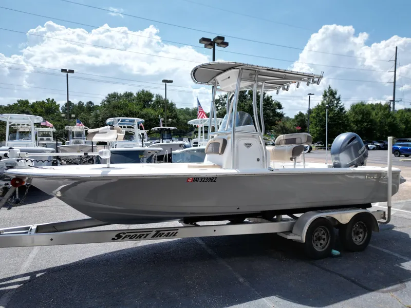 Slide: The Image of 2018 Tidewater 2110 Baymax boat on trailer, parked outdoors under a cloudy sky. - 18