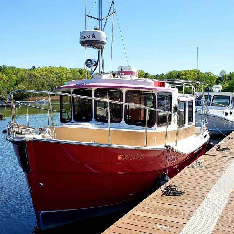The Image of 2010 Ranger Tugs R-25 boat docked, featuring a red hull and Garmin equipment. - 0