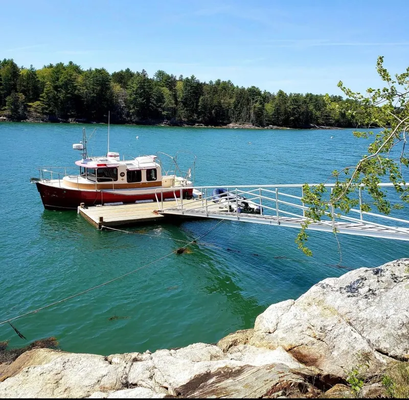 Slide: The Image of 2010 Ranger Tugs R-25 docked on serene lake with lush forest backdrop. - 1