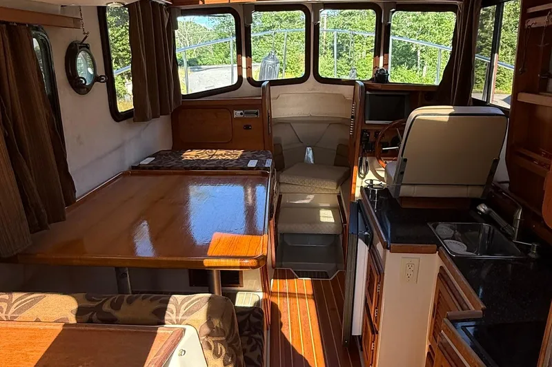 Slide: The Image of Interior of 2010 Ranger Tugs R-25 boat, featuring wood finishes and compact kitchen area. - 13