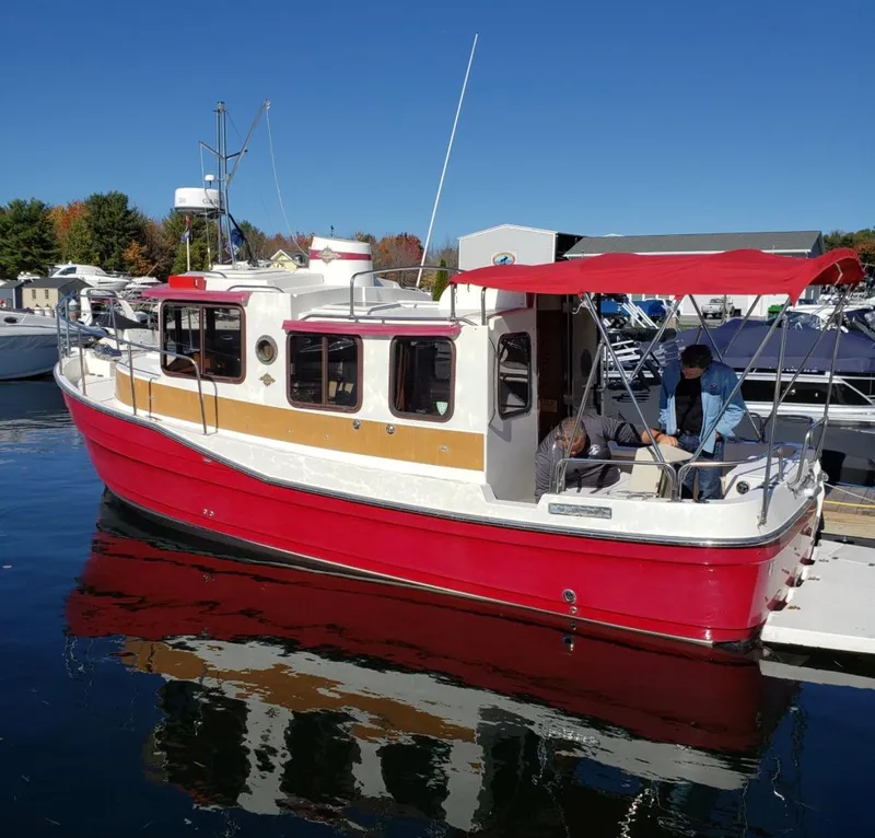 Slide: The Image of 2010 Ranger Tugs R-25 boat with red hull and canopy docked on a sunny day. - 3