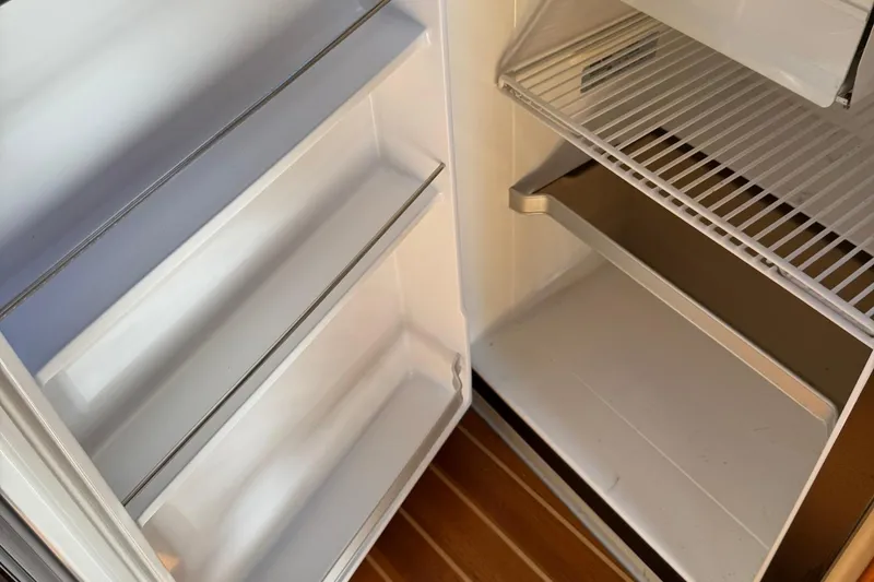 Slide: The Image of Empty refrigerator inside a 2010 Ranger Tugs R-25 boat, showing shelves and door storage. - 37